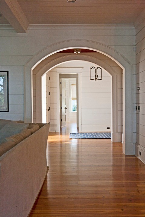 This is an example of a large tropical hallway in Charleston with white walls and medium hardwood floors.