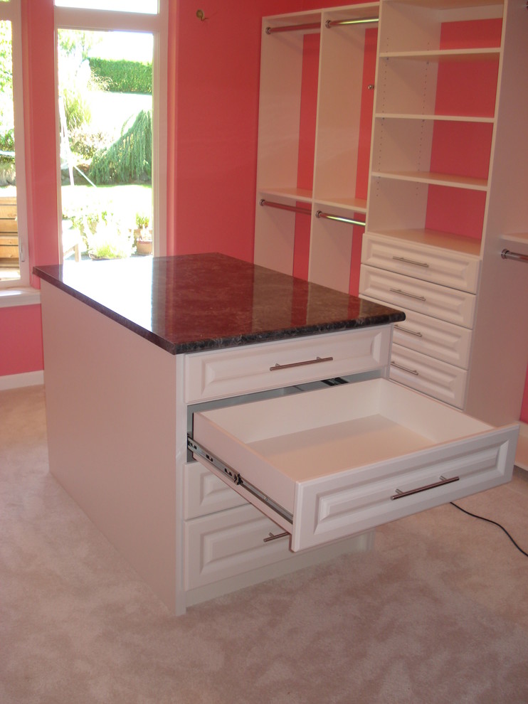 This is an example of an expansive contemporary women's walk-in wardrobe in Seattle with raised-panel cabinets, white cabinets, carpet and white floor.