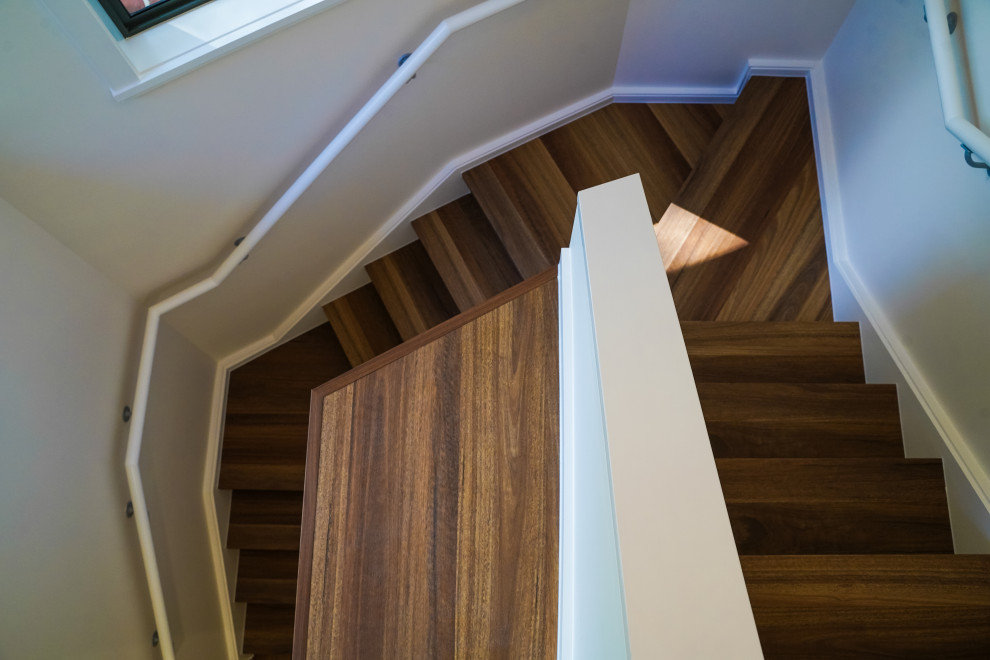 Mid-sized trendy wooden curved glass railing staircase photo in Sydney with wooden risers