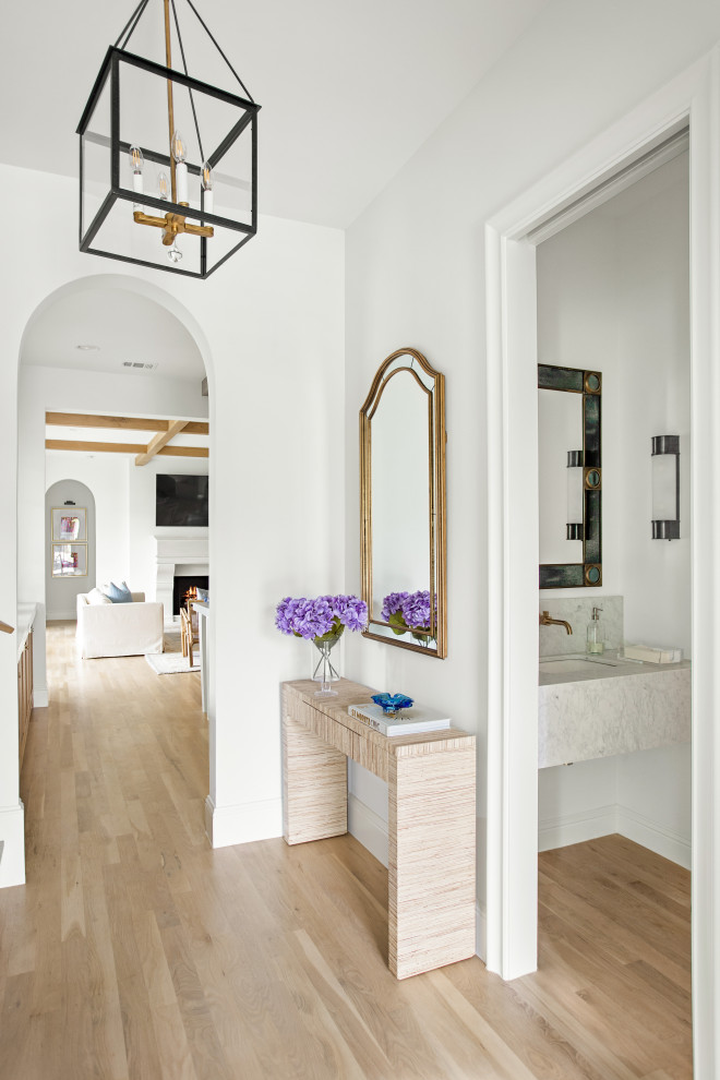 ダラスにあるラグジュアリーな広いトランジショナルスタイルのおしゃれな玄関ロビー (白い壁、淡色無垢フローリング、金属製ドア、茶色い床) の写真
