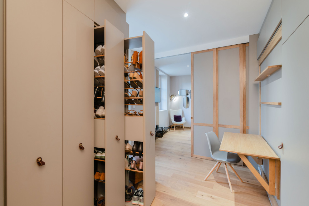 Foto de vestidor unisex minimalista grande con armarios con rebordes decorativos, puertas de armario grises y suelo de madera clara