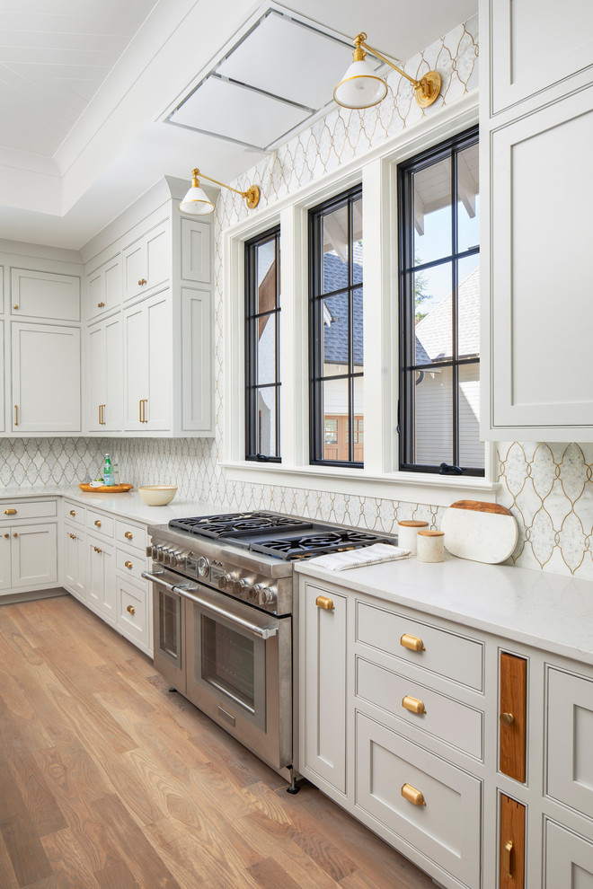 Open concept kitchen - large transitional u-shaped medium tone wood floor and brown floor open concept kitchen idea in Charlotte with a farmhouse sink, beaded inset cabinets, gray cabinets, quartz countertops, mosaic tile backsplash, paneled appliances, an island and white countertops