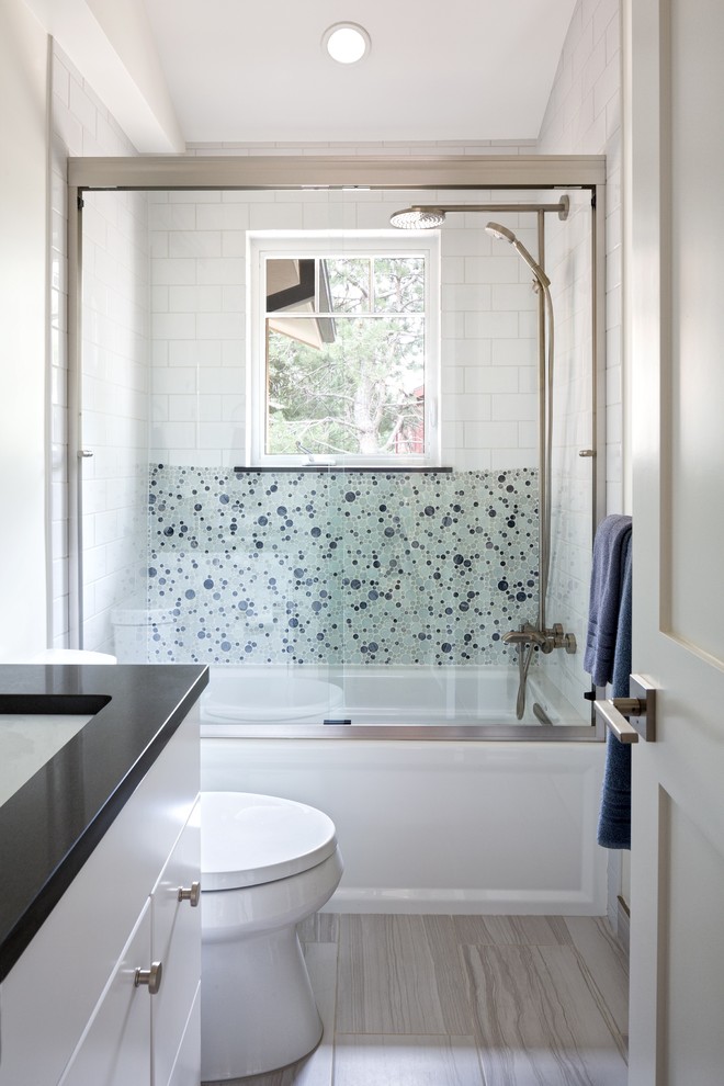 This is an example of a small transitional kids bathroom in Denver with flat-panel cabinets, white cabinets, an alcove tub, a shower/bathtub combo, a two-piece toilet, white tile, glass tile, white walls, porcelain floors, an undermount sink, beige floor and a sliding shower screen.