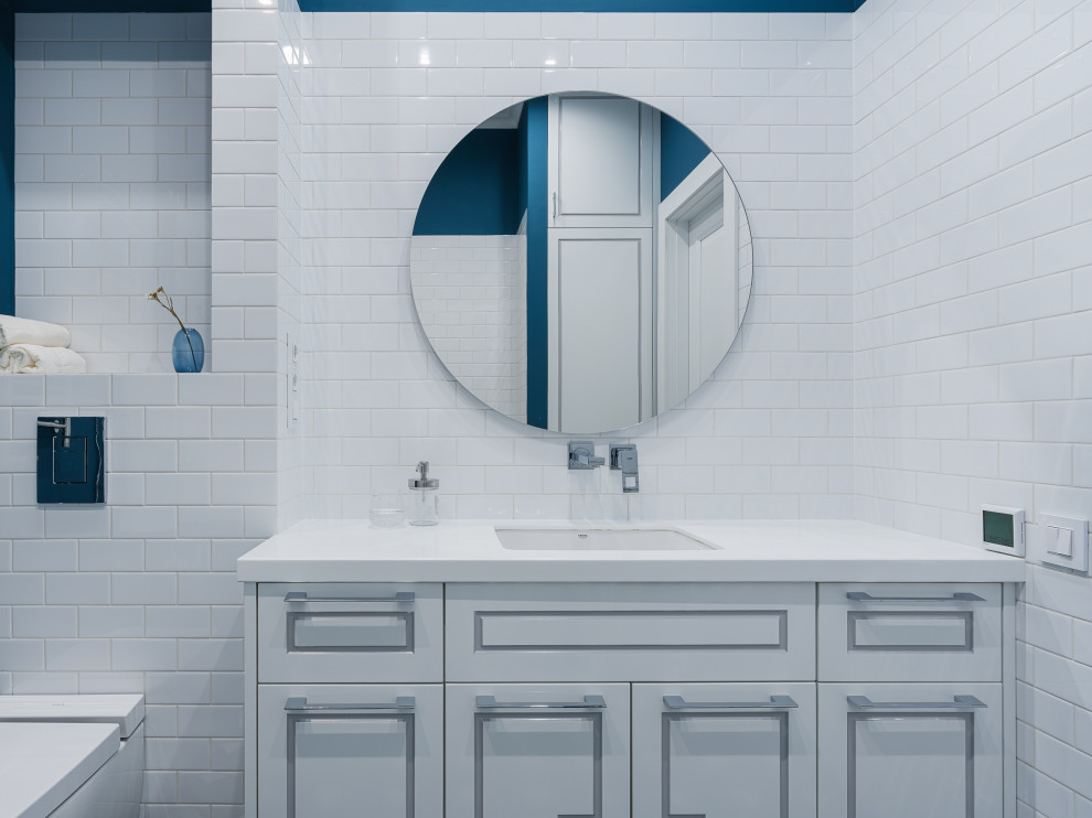 Идея дизайна: детская ванная комната среднего размера с фасадами с утопленной филенкой, белыми фасадами, отдельно стоящей ванной, душем в нише, инсталляцией, белой плиткой, керамической плиткой, синими стенами, полом из керамогранита, врезной раковиной, столешницей из искусственного камня, синим полом, душем с распашными дверями, белой столешницей, гигиеническим душем, тумбой под одну раковину, подвесной тумбой и обоями на стенах