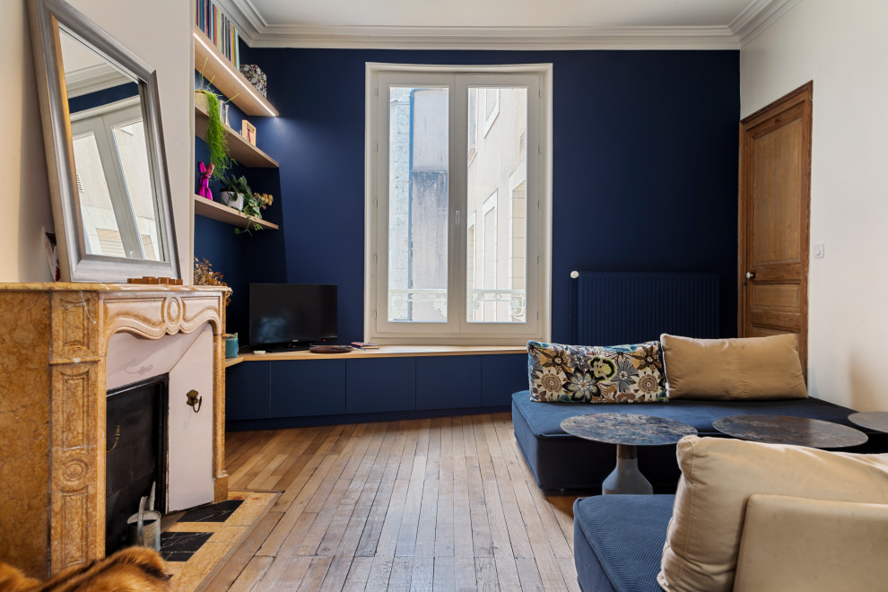 Cette image montre un salon traditionnel de taille moyenne et ouvert avec un mur bleu, parquet clair et un manteau de cheminée en pierre.