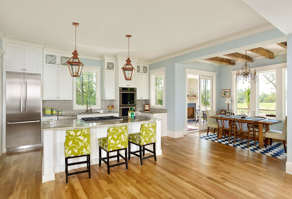 Design ideas for a mid-sized beach style galley eat-in kitchen in Charleston with shaker cabinets, white cabinets, quartzite benchtops, stainless steel appliances, medium hardwood floors, with island, grey splashback, subway tile splashback and brown floor.