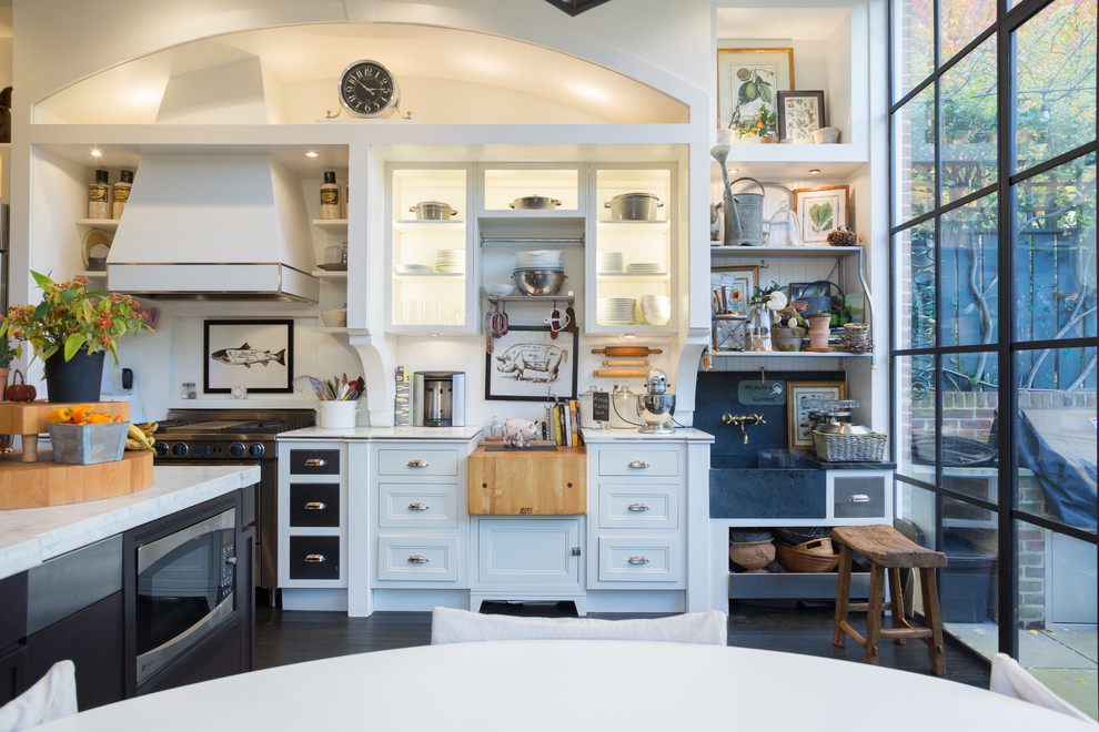 This is an example of an eclectic u-shaped open plan kitchen in DC Metro with a farmhouse sink, beaded inset cabinets, white cabinets, marble benchtops, white splashback, stone slab splashback, stainless steel appliances, dark hardwood floors and with island.