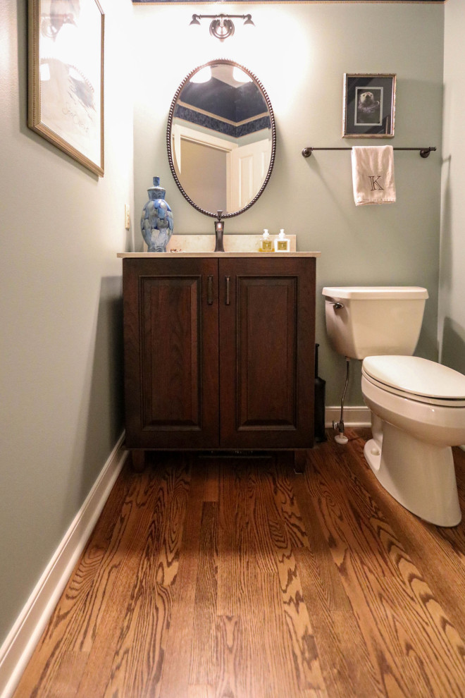 Photo of a small cloakroom in Cleveland with raised-panel cabinets, dark wood cabinets, a two-piece toilet, green walls, dark hardwood flooring, a submerged sink, engineered stone worktops, beige worktops and a freestanding vanity unit.