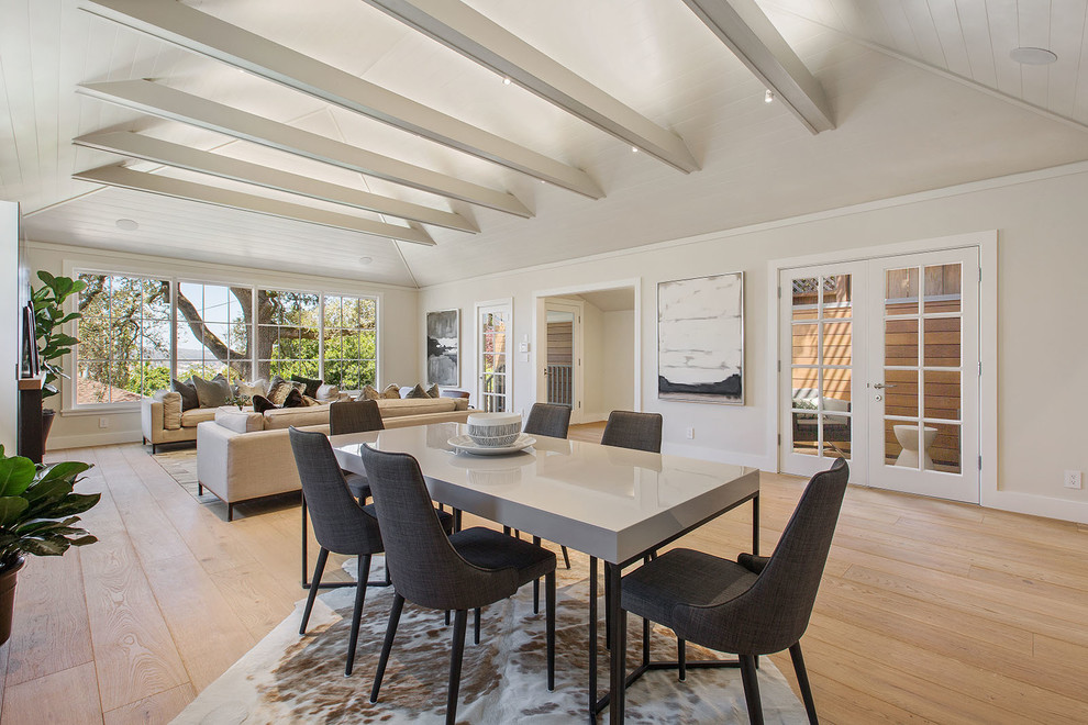 Photo of a transitional dining room in San Francisco with beige walls, light hardwood floors, a standard fireplace, a tile fireplace surround and beige floor.