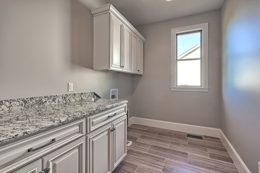 Large transitional single-wall dedicated laundry room in Other with white cabinets, granite benchtops, grey walls, dark hardwood floors and a side-by-side washer and dryer.