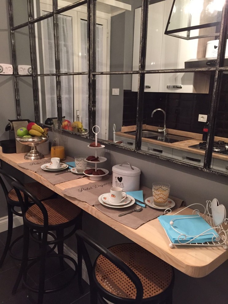 Small industrial galley separate kitchen in Rome with a drop-in sink, flat-panel cabinets, white cabinets, marble benchtops, stainless steel appliances and slate floors.