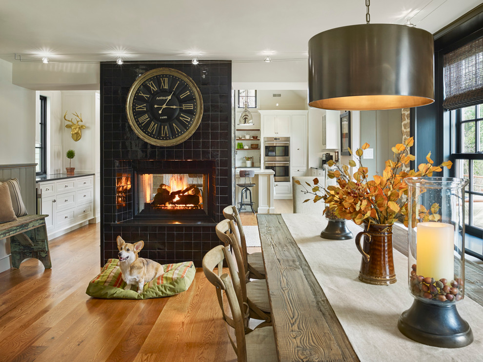 Inspiration for a large country kitchen/dining combo in Philadelphia with white walls, medium hardwood floors, a two-sided fireplace and a tile fireplace surround.