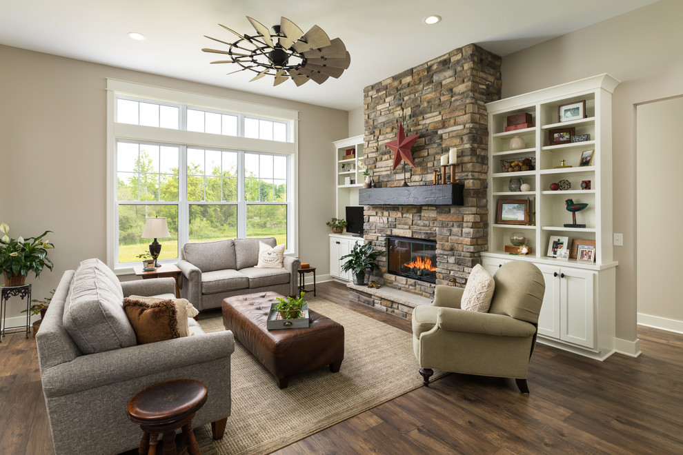 Mid-sized country open concept living room in Grand Rapids with beige walls, a standard fireplace, a built-in media wall, brown floor, laminate floors and a stone fireplace surround.
