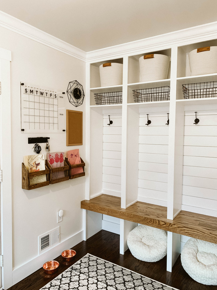 This is an example of a mid-sized country mudroom in Detroit with white walls, dark hardwood floors and brown floor.
