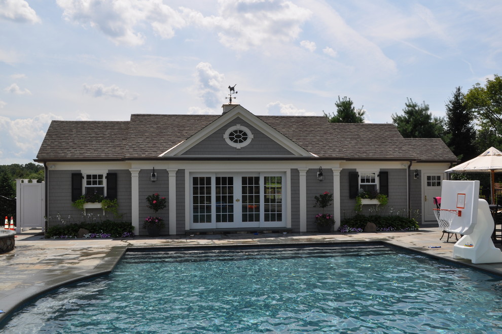 Inspiration for a large traditional backyard rectangular lap pool in Boston with a pool house and natural stone pavers.