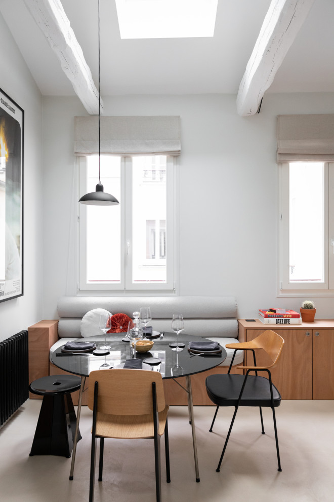 Moderne Frühstücksecke mit weißer Wandfarbe, Betonboden, beigem Boden und freigelegten Dachbalken in Paris