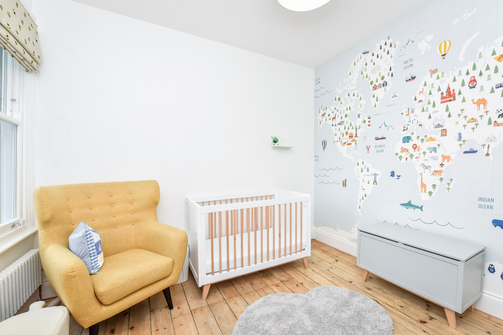This is an example of a mid-sized transitional gender-neutral nursery in London with white walls, medium hardwood floors and brown floor.