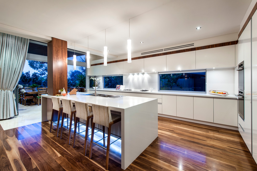 Photo of a mid-sized contemporary galley eat-in kitchen in Perth with a drop-in sink, flat-panel cabinets, white cabinets, quartz benchtops, stainless steel appliances, dark hardwood floors and with island.