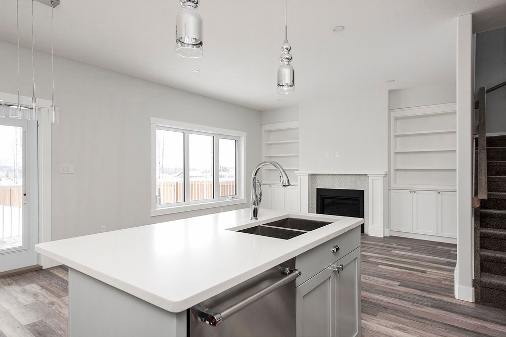 Mid-sized transitional l-shaped medium tone wood floor and brown floor open concept kitchen photo in Calgary with an undermount sink, shaker cabinets, white cabinets, quartzite countertops, white backsplash, subway tile backsplash, stainless steel appliances, an island and white countertops