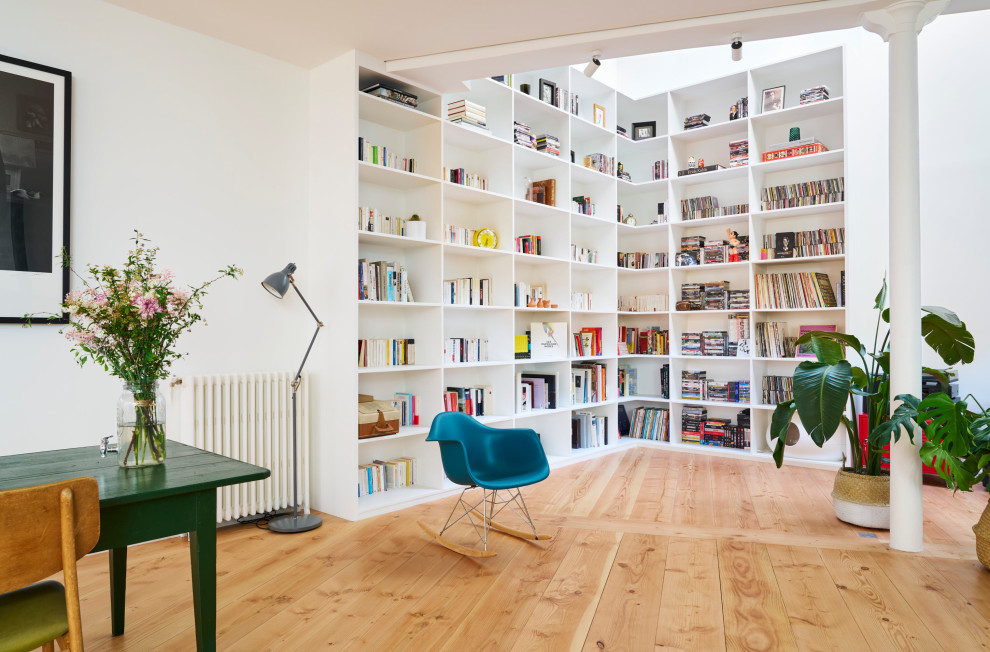 Inspiration pour une salle de séjour bohème ouverte avec une bibliothèque ou un coin lecture, un mur blanc, un sol en bois brun et un sol marron.