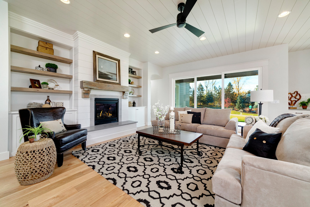 Photo of a transitional family room in Boise with white walls, light hardwood floors and a standard fireplace.