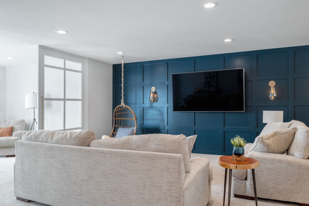 This is an example of a large transitional open concept family room in Minneapolis with a home bar, blue walls, carpet, a wall-mounted tv and beige floor.