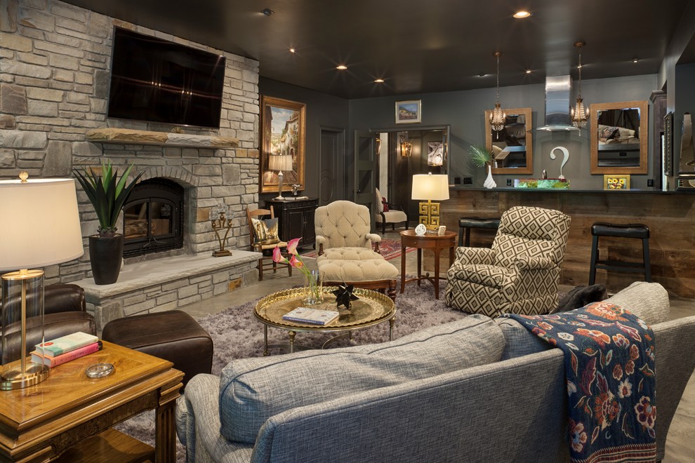 This is an example of a country enclosed family room in Other with a home bar, black walls, a wood stove, a stone fireplace surround, a wall-mounted tv and grey floor.