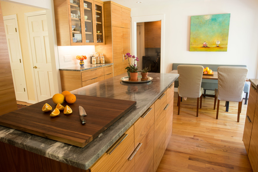 Eat-in kitchen - mid-sized transitional u-shaped medium tone wood floor eat-in kitchen idea with an undermount sink, flat-panel cabinets, medium tone wood cabinets, quartzite countertops, white backsplash, ceramic backsplash, stainless steel appliances and an island