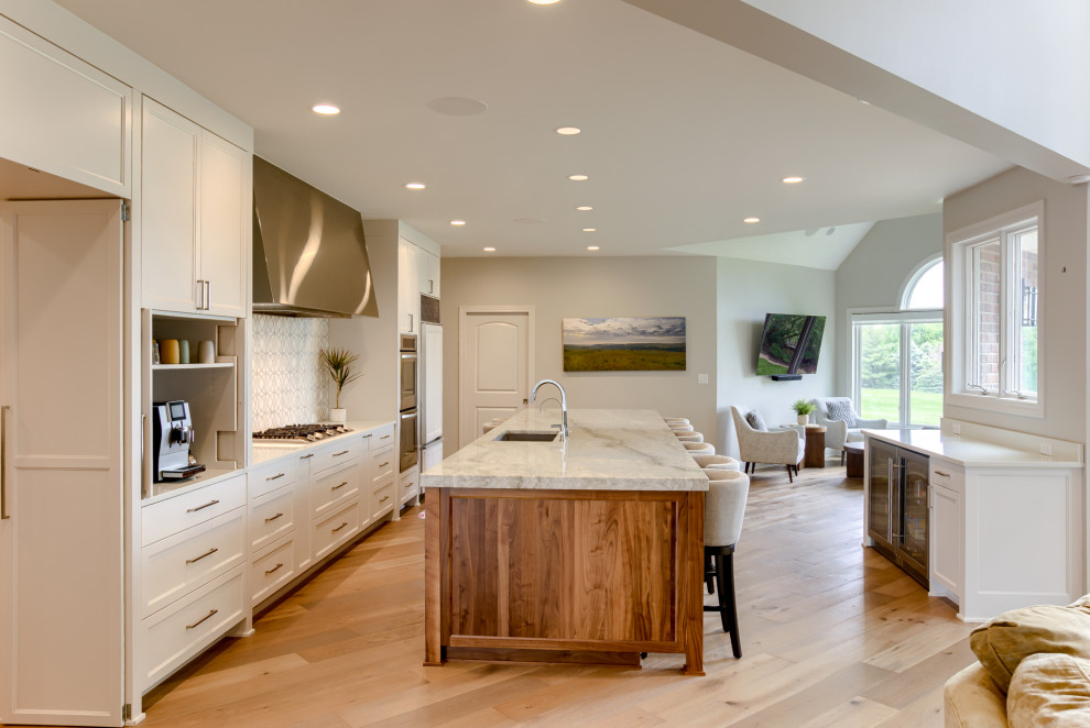 Large transitional light wood floor eat-in kitchen photo with a single-bowl sink, recessed-panel cabinets, white cabinets, quartzite countertops, stainless steel appliances and an island
