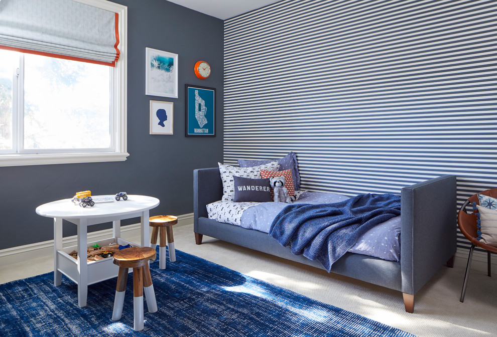 This is an example of a transitional kids' bedroom for kids 4-10 years old and boys in San Francisco with blue walls, carpet and beige floor.