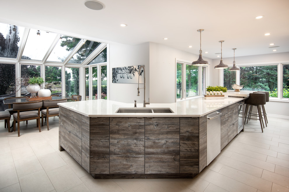 Example of a large l-shaped kitchen pantry design with an undermount sink, shaker cabinets, white cabinets, quartz countertops, stainless steel appliances and an island
