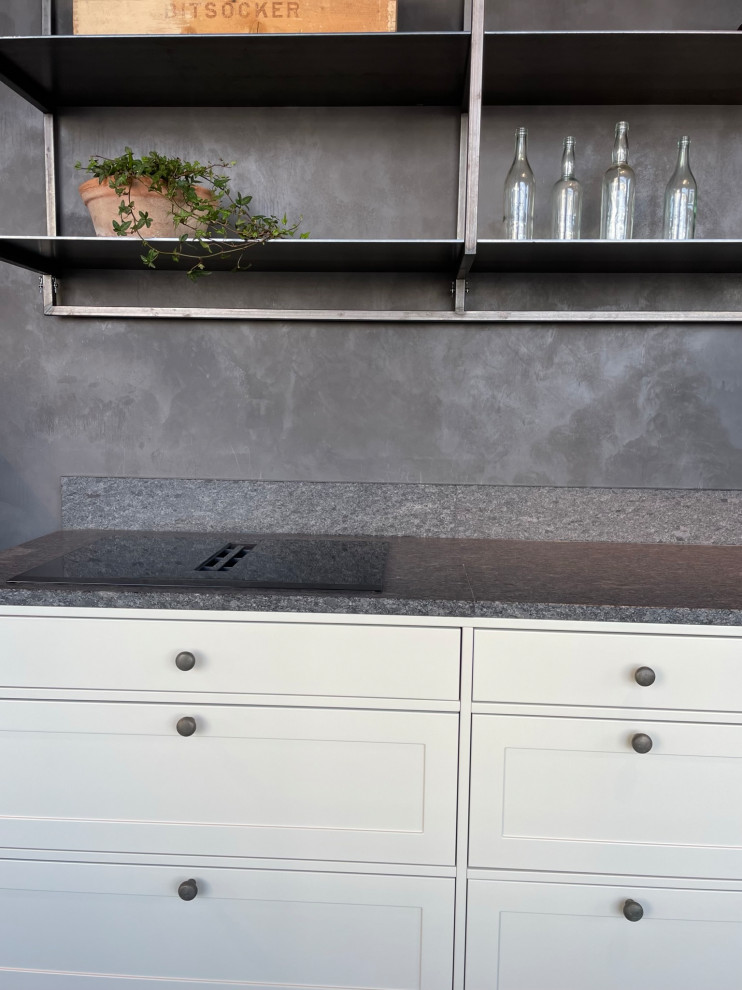Bild på ett avskilt, mellanstort lantligt grå linjärt grått kök, med en undermonterad diskho, skåp i shakerstil, beige skåp, granitbänkskiva, grått stänkskydd, integrerade vitvaror, betonggolv och grått golv