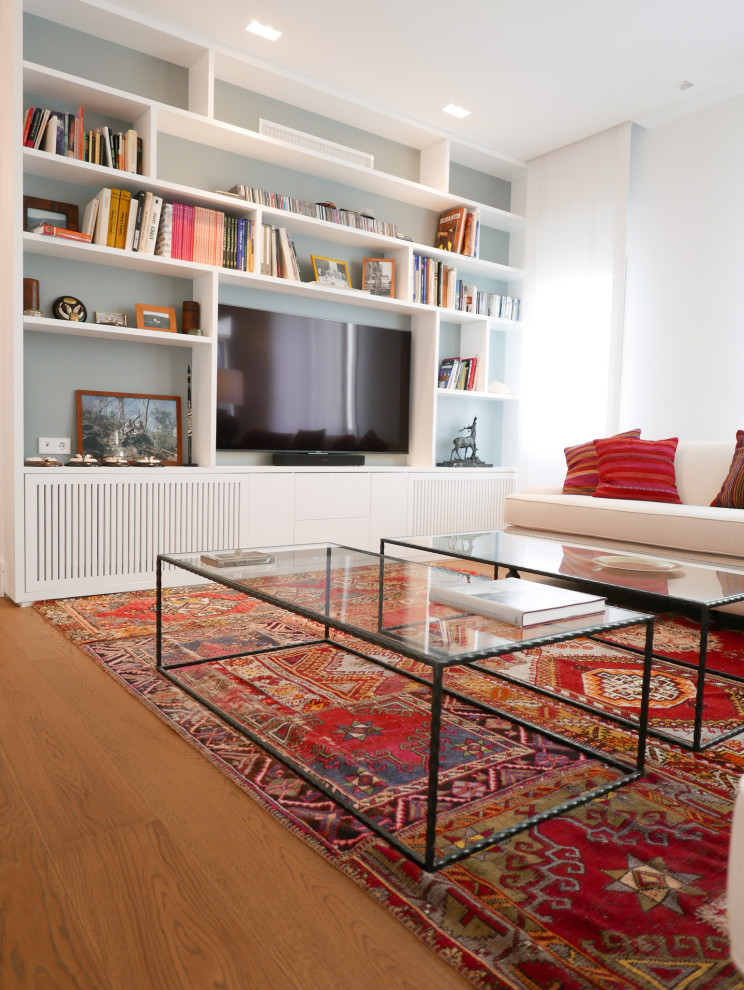 Esempio di un soggiorno eclettico di medie dimensioni e aperto con libreria, pareti bianche, pavimento in legno massello medio, parete attrezzata e pavimento marrone
