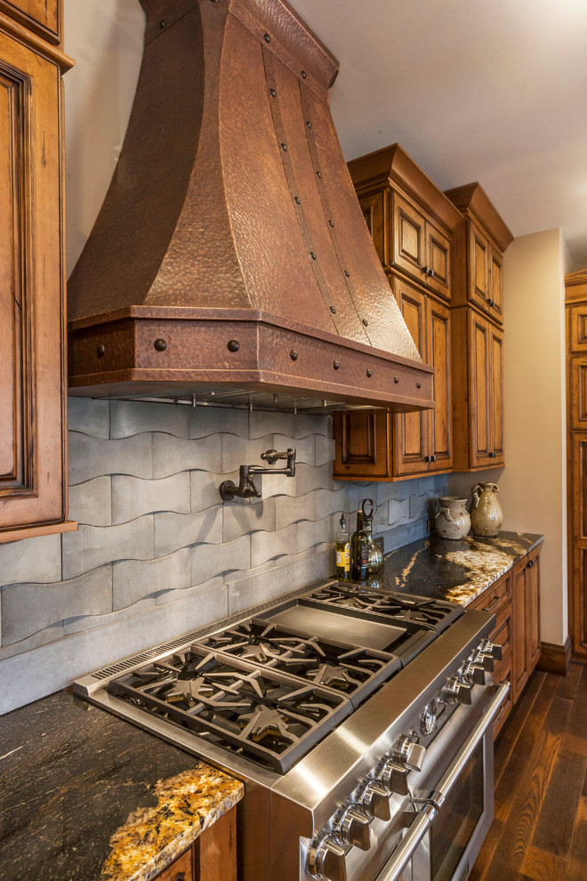 Example of a large mountain style medium tone wood floor eat-in kitchen design with a drop-in sink, raised-panel cabinets, medium tone wood cabinets, stainless steel appliances and an island