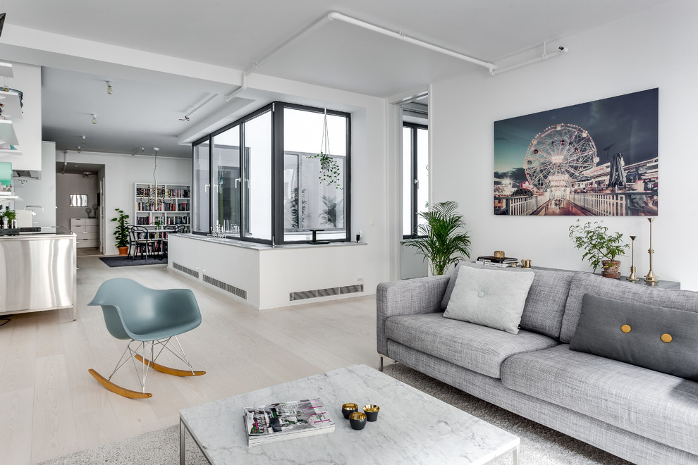 This is an example of a mid-sized industrial formal open concept living room in Stockholm with light hardwood floors, white walls and no tv.