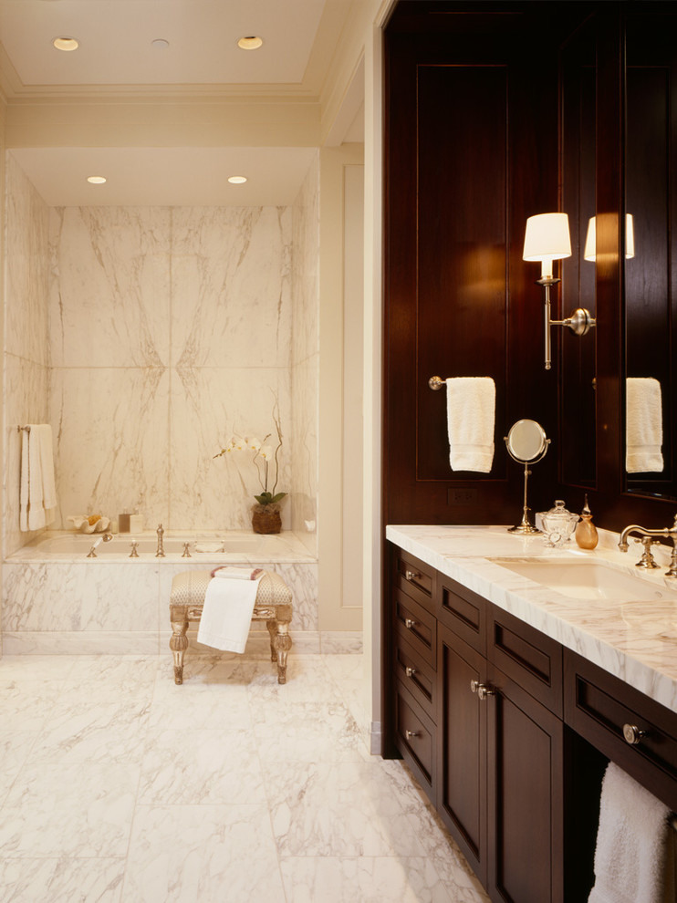 This is an example of a large transitional master bathroom in Chicago with marble benchtops, beige walls, marble floors, brown cabinets, an alcove tub and an undermount sink.
