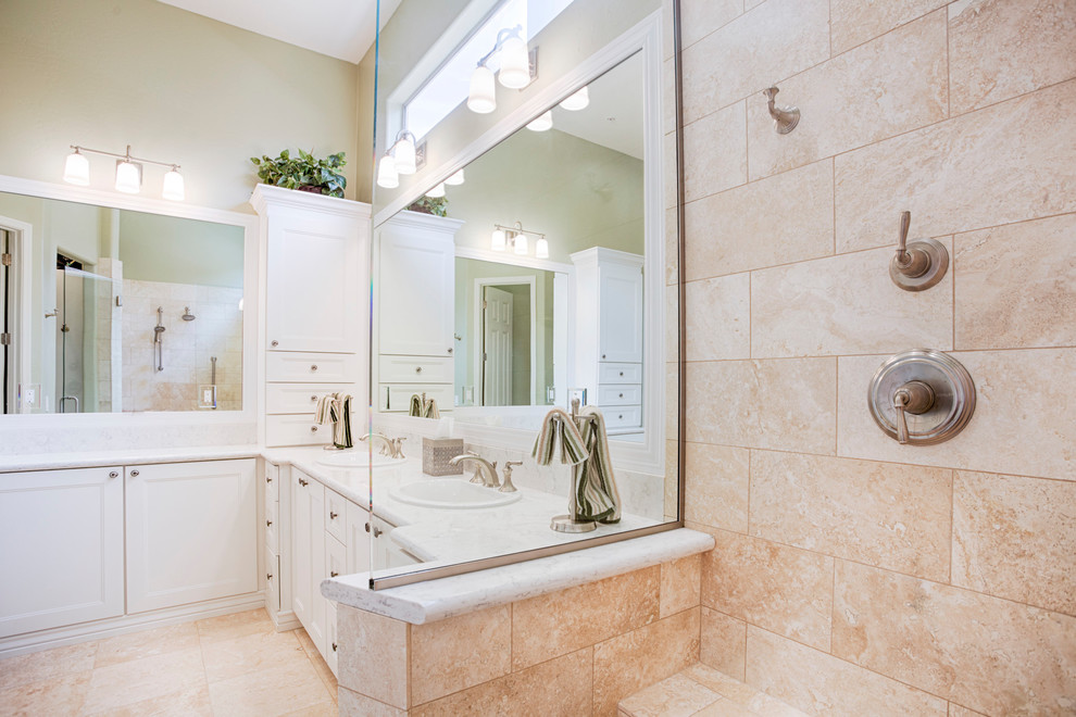 Corner shower - large transitional master beige tile and travertine tile travertine floor corner shower idea in Phoenix with recessed-panel cabinets, white cabinets, green walls, an undermount sink and granite countertops
