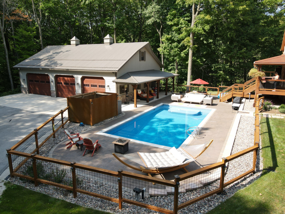 Aménagement d'un grand piscine avec aménagement paysager latéral montagne rectangle avec des pavés en béton.