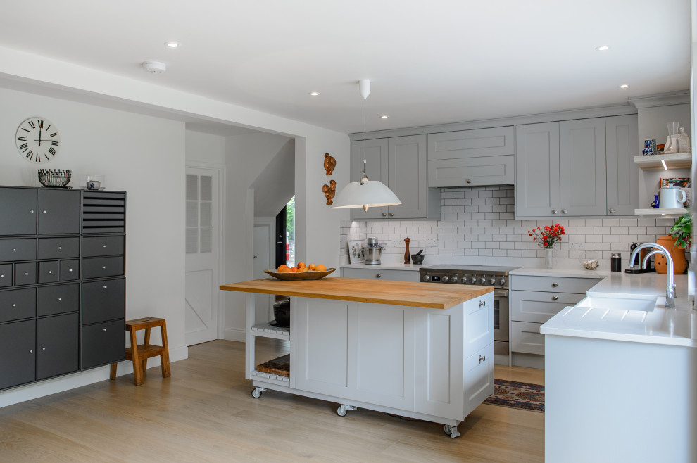 This is an example of a mid-sized modern l-shaped open plan kitchen in Cornwall with shaker cabinets, grey cabinets, granite benchtops and with island.