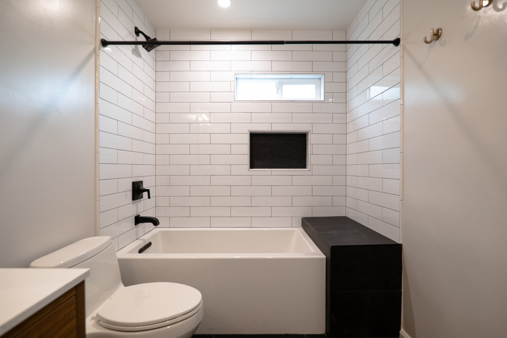 Inspiration for a medium sized traditional ensuite bathroom in Los Angeles with freestanding cabinets, medium wood cabinets, a submerged bath, a shower/bath combination, a one-piece toilet, white tiles, metro tiles, white walls, porcelain flooring, a built-in sink, quartz worktops, black floors, a shower curtain, white worktops, a shower bench, a single sink and a freestanding vanity unit.