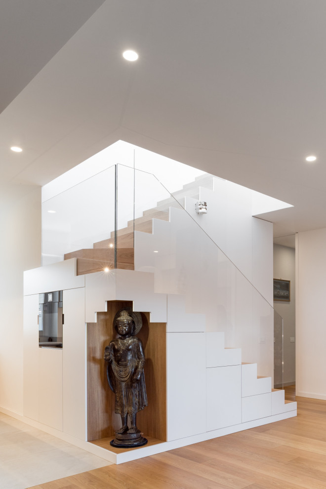 Imagen de escalera en U contemporánea pequeña con escalones de madera, contrahuellas de madera, barandilla de vidrio y madera