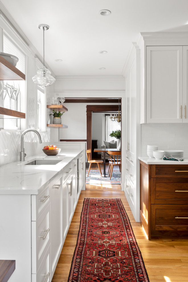 Mid-sized transitional medium tone wood floor kitchen photo in Boston with a single-bowl sink, recessed-panel cabinets, white cabinets, quartzite countertops, white backsplash, subway tile backsplash, stainless steel appliances, no island and white countertops