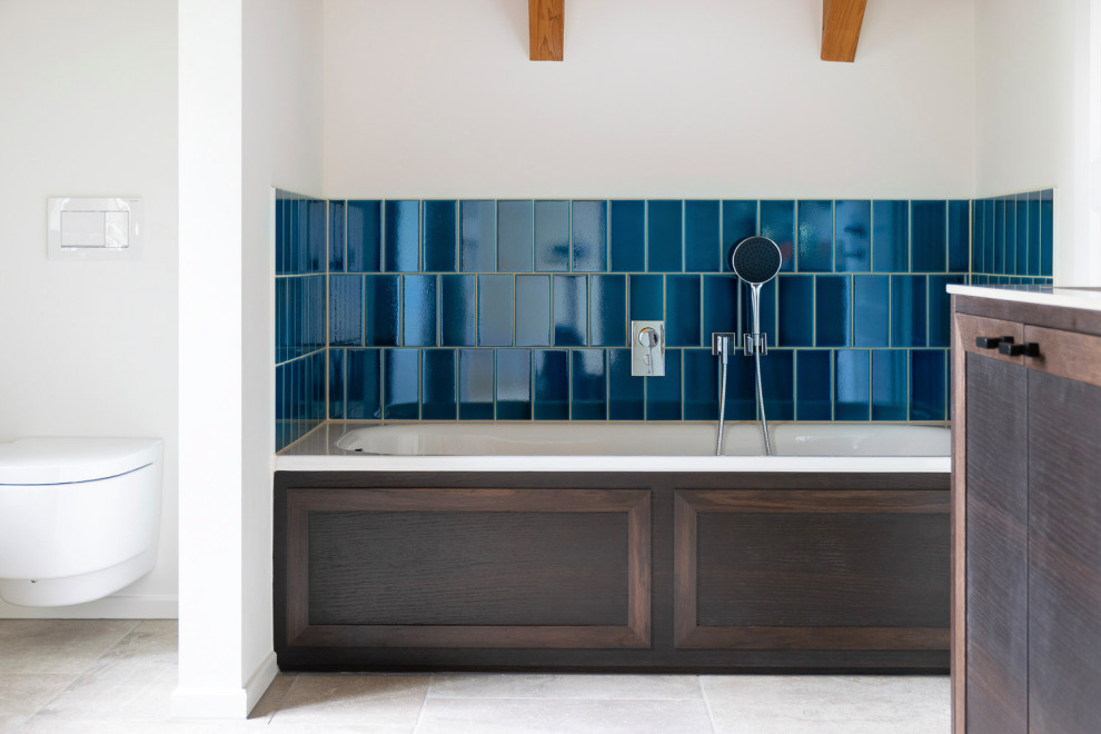 Badezimmer En Suite With Kassettenfronten, dunklen Holzschränken, Einbaubadewanne, bodengleicher Dusche, blauen Fliesen, Keramikfliesen, weißer Wandfarbe, Einbauwaschbecken, Quarzwerkstein-Waschtisch, grauem Boden, Falttür-Duschabtrennung, beiger Waschtischplatte, Doppelwaschbecken, freistehendem Waschtisch and freigelegten Dachbalken in Munich