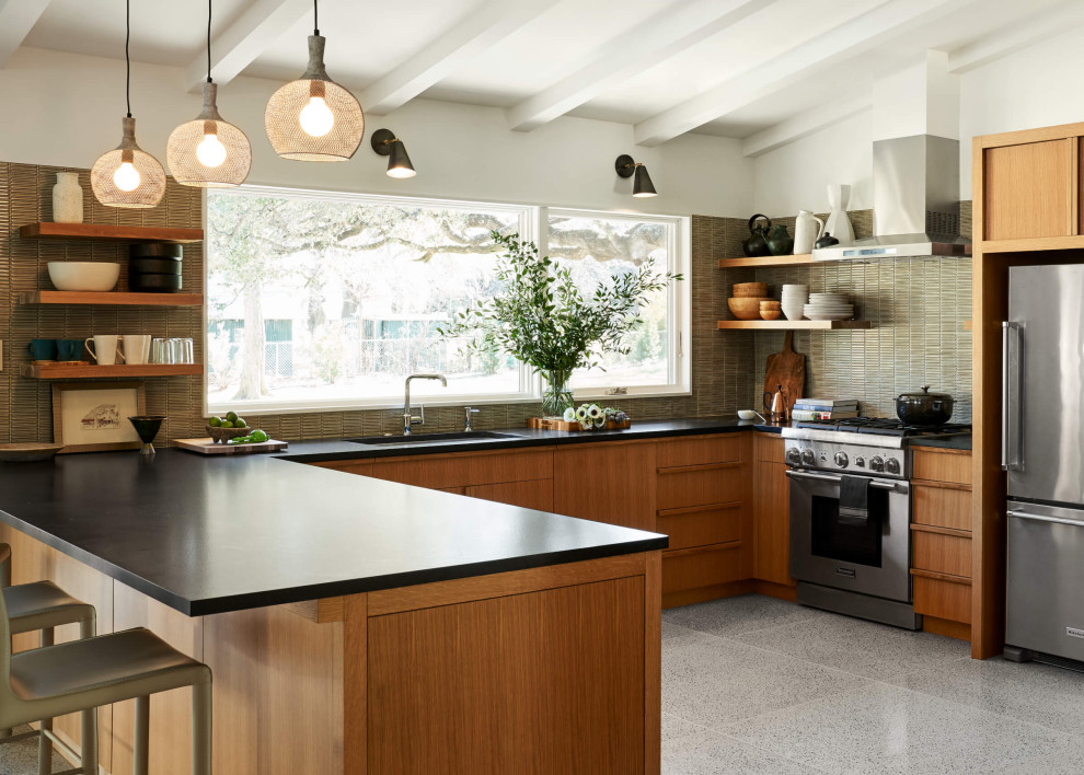 Design ideas for a mid-sized midcentury u-shaped eat-in kitchen in Austin with a drop-in sink, flat-panel cabinets, brown cabinets, green splashback, stainless steel appliances, terrazzo floors, no island, white floor and black benchtop.