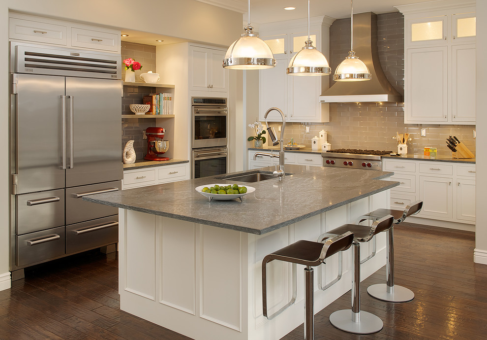 Mid-sized transitional l-shaped dark wood floor and brown floor open concept kitchen photo in San Francisco with an undermount sink, recessed-panel cabinets, white cabinets, quartz countertops, beige backsplash, subway tile backsplash, stainless steel appliances and an island