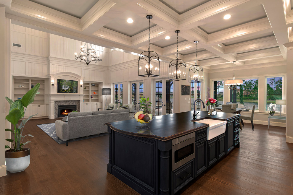 This is an example of a traditional open plan kitchen in Jacksonville with a farmhouse sink, raised-panel cabinets, blue cabinets, black appliances, medium hardwood floors, with island, brown floor and brown benchtop.