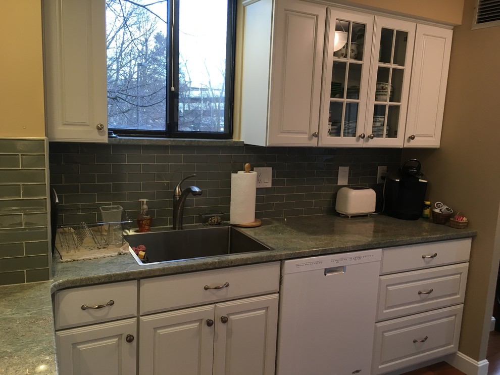 Inspiration for a transitional u-shaped medium tone wood floor kitchen remodel in Boston with a drop-in sink, raised-panel cabinets, white cabinets, granite countertops, green backsplash, glass tile backsplash, white appliances, a peninsula and green countertops