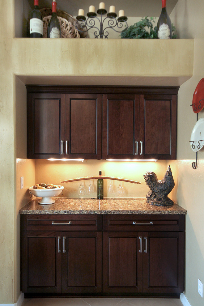Kitchen pantry - large transitional concrete floor kitchen pantry idea in Phoenix with an undermount sink, louvered cabinets, dark wood cabinets, granite countertops, beige backsplash, stone tile backsplash, stainless steel appliances and an island