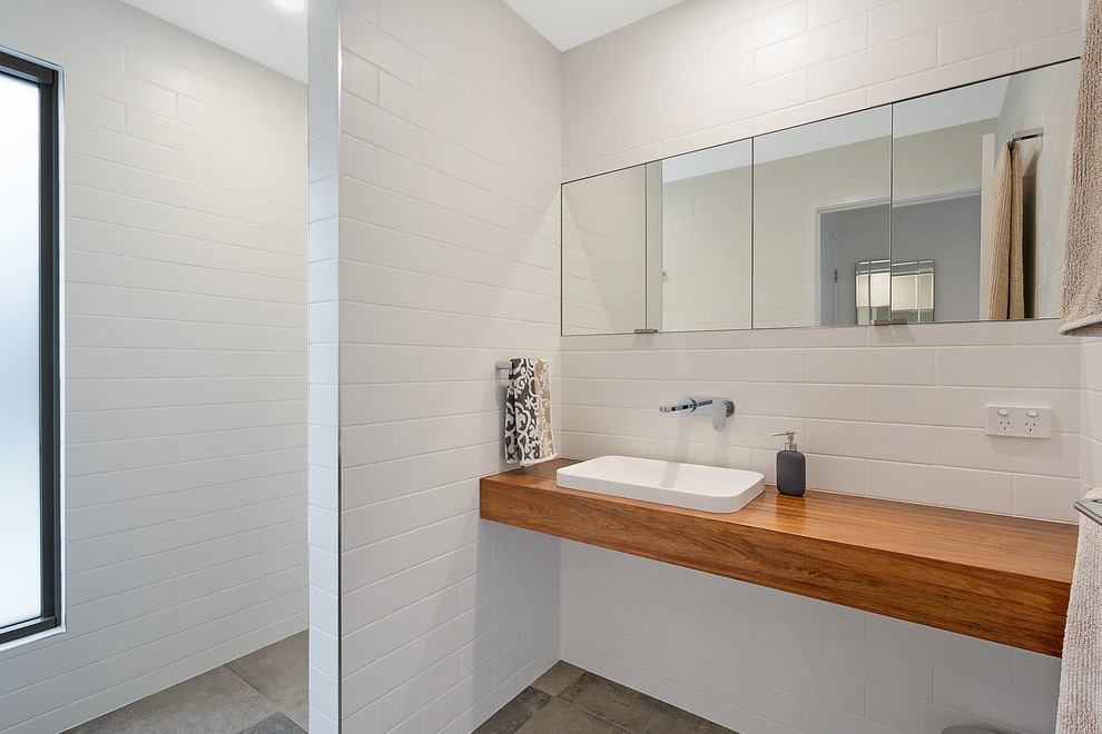 Small modern 3/4 bathroom in Sydney with medium wood cabinets, white tile, ceramic tile and wood benchtops.