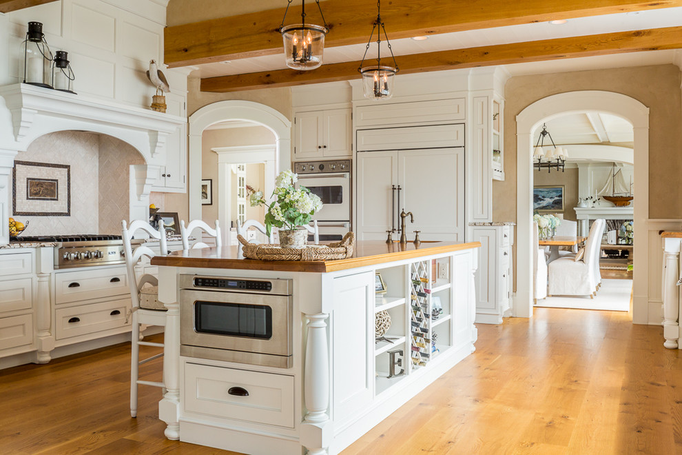 Beach style l-shaped eat-in kitchen in Portland Maine with recessed-panel cabinets, white cabinets, wood benchtops, white appliances, light hardwood floors and with island.